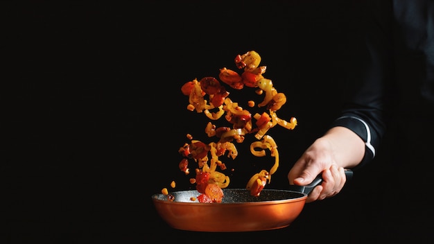 Chef cooking vegetables on a pan.