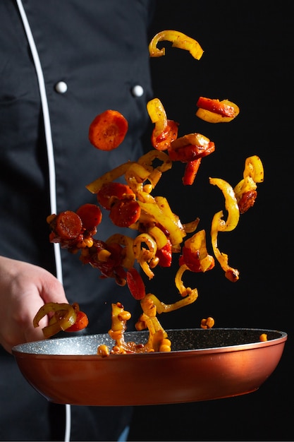 Chef cooking vegetables on a pan.