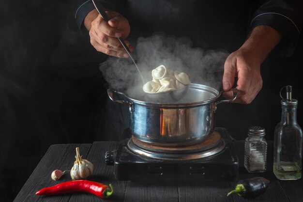 Chef cooks meat dumplings in a saucepan in the restaurant kitchen. Close-up of the hands of the cook during work. Free advertising space.