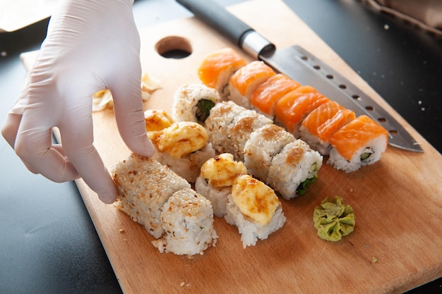 The chef cooks sushi Chef takes sushi with one hand in gloves