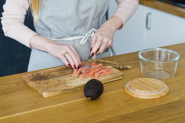 The chef cuts Atlantic salmon for a sandwich with avacado and egg. 