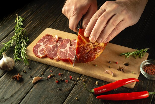 Photo the chef cuts the baked veal meat with a knife for cooking dinner in the kitchen fast street food concept on dark background