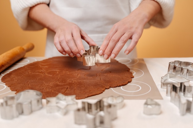 The chef cuts gingerbread cookies for a festive christmas table using a metal mold