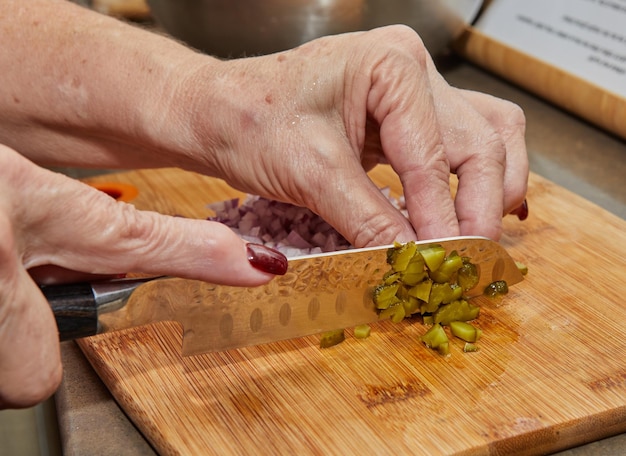 Chef cuts pickles with knife to prepare everything according to the recipe