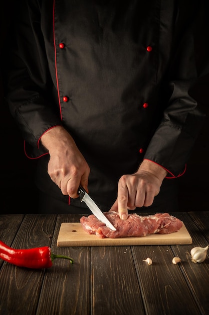 The chef cuts raw beef meat on a cutting board before baking Asian cuisine Hotel menu recipe idea