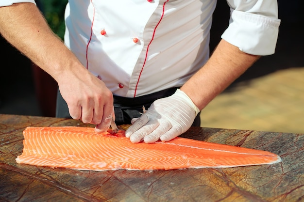 Photo the chef cuts the salmon on the table.