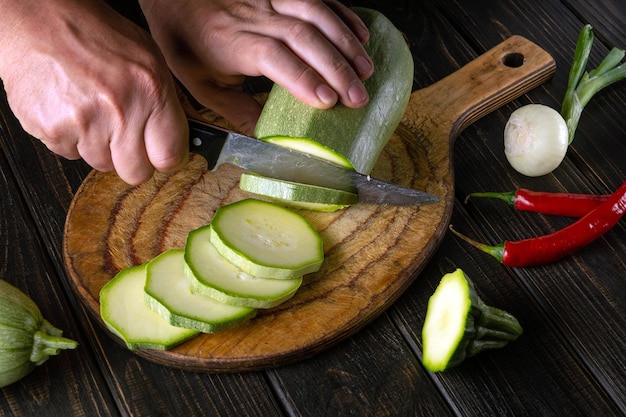 The chef cuts vegetable marrow into small pieces with a knife before preparing a delicious dinner