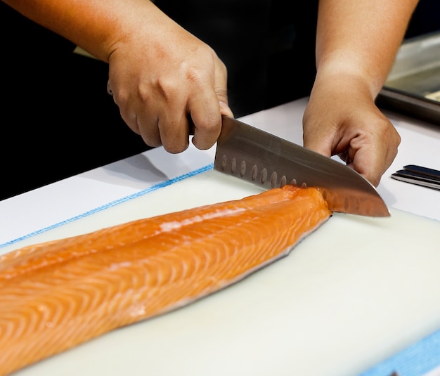 Chef cutting fresh salmon fillet in kitchen, chef cuts the salmon 