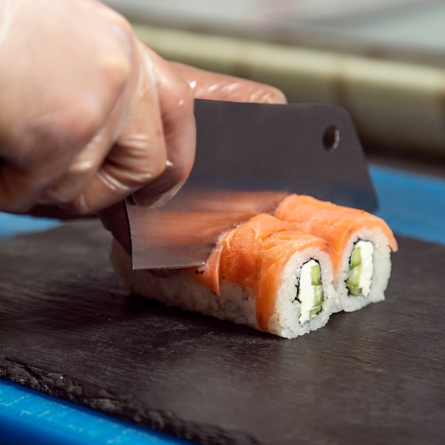 Chef cutting the Philadelphia light sushi roll close up