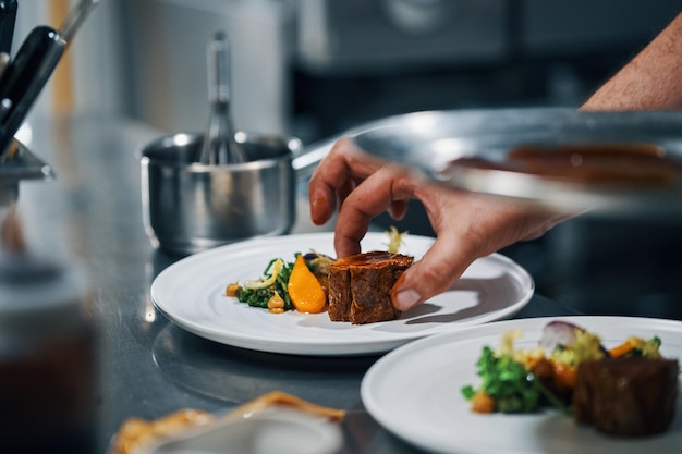 Chef dishing up steak in professional kitchen