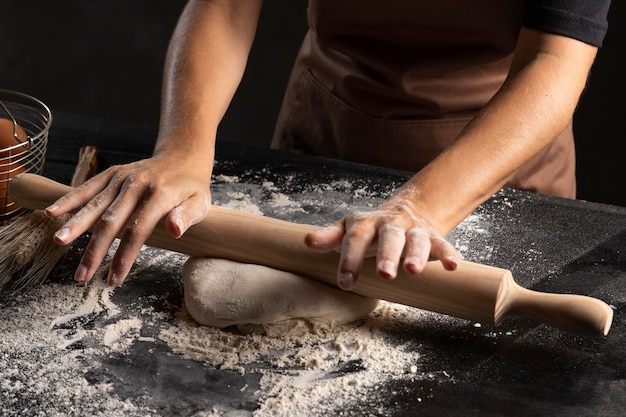 Chef flattening the dough using rolling pin