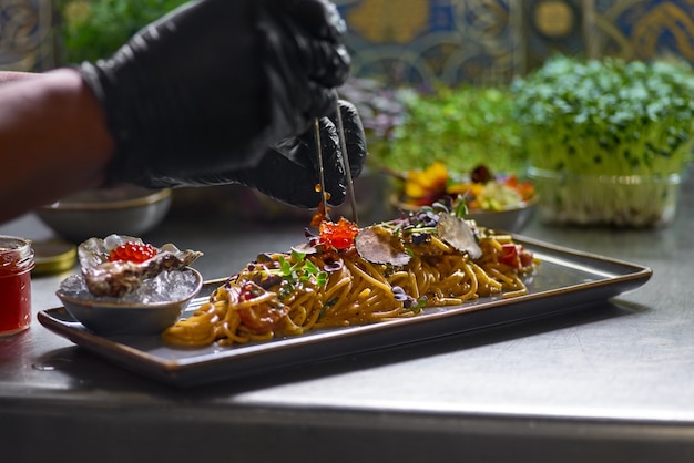 The chef garnishes with red caviar a seafood spaghetti dish, Selective focus.