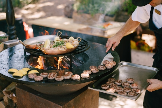 The chef grills meatballs for mini burgers on the grill