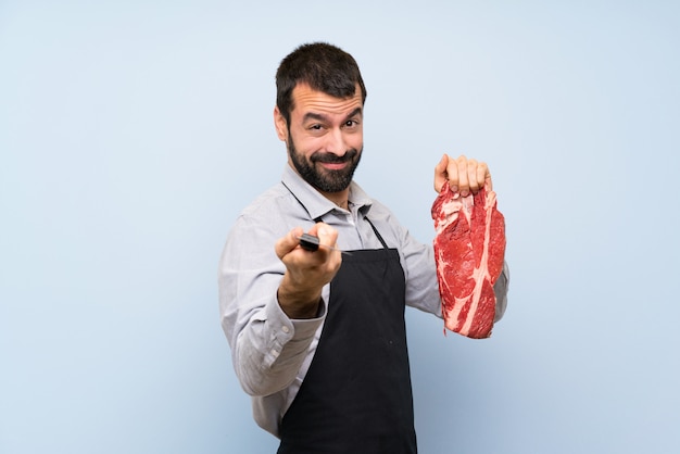 Chef holding a raw meat pointing to the front