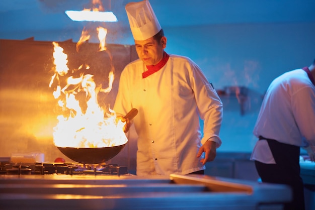 chef in hotel kitchen prepare vegetable  food with fire