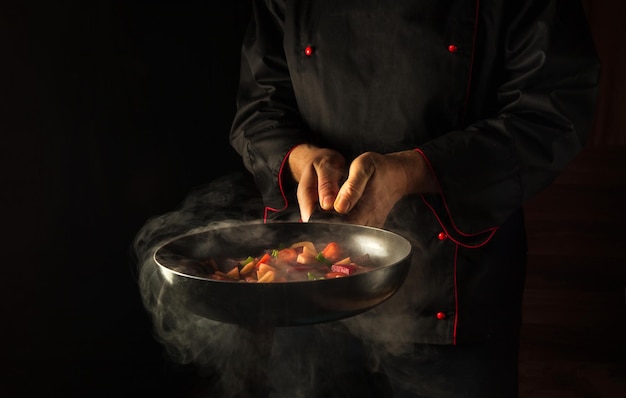 The chef is holding a hot frying pan with steam