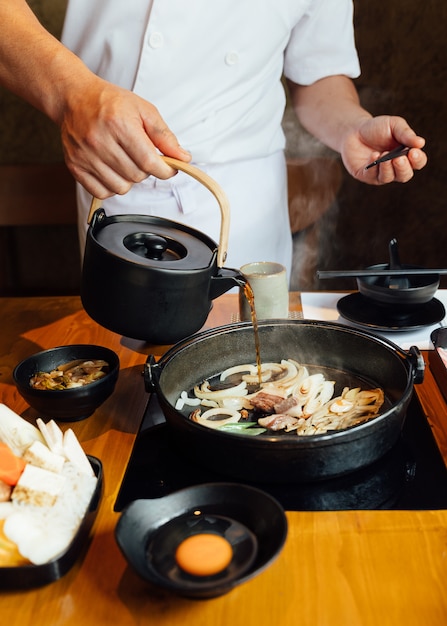 Photo chef is pouring shabu sauce mix with fried onion, scallion and beef fat.