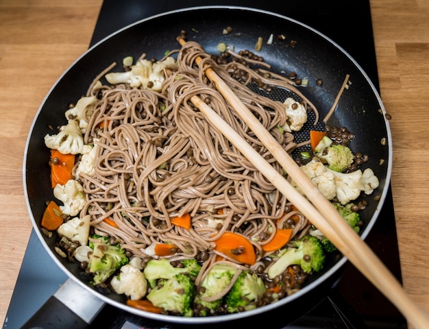 Chef at the kitchen preparing japanese buckwheat pasta with lentils