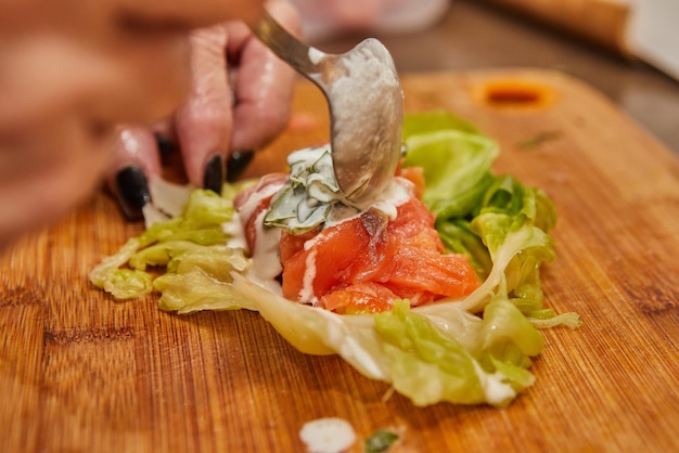 Chef makes Cabbage rolls with salmon carrots and sauce in the kitchen French recipe