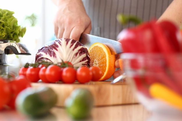 Chef man cut vegetables and fruits on cutting board closeup