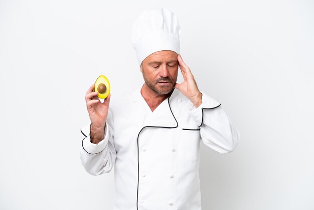 Chef man holding an avocado isolated on white background with headache