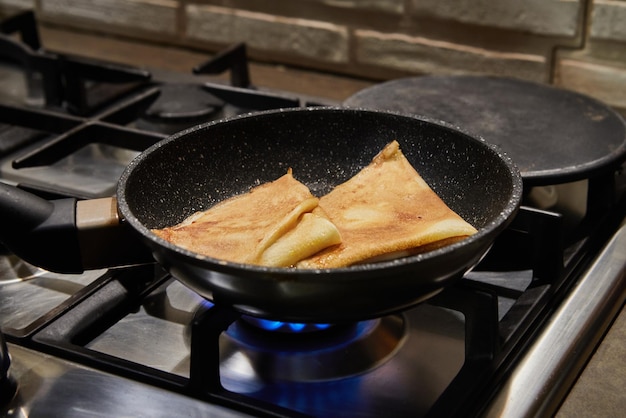 Chef panfrying Crepe Suzette pancakes with cognac and citrus sauce