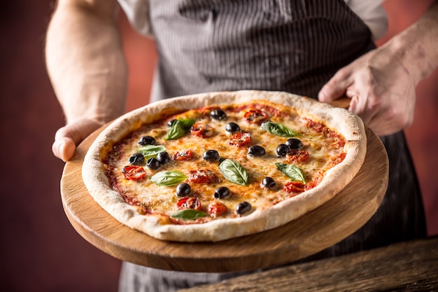 Chef and pizza. Chef offering pizza in hotel or restaurant.