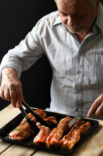 The chef places the marinated pork ribs on a baking sheet. Cooking the ribs.