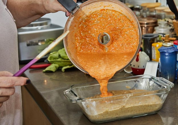 Chef pours the mass for making Casserole from eggplant and zucchini in two colors into the mold