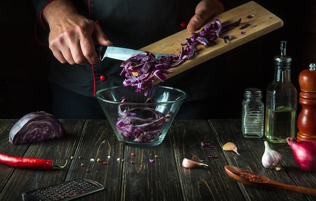 The chef pours the red cabbage into the bowl Cooking vegetable salad in the restaurant kitchen