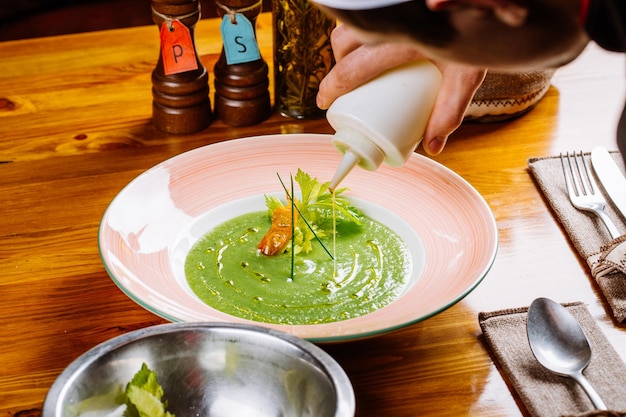 Chef prepares broccoli green soup puree with celery on the wooden background vegetarian diet cooking culinary and food concept