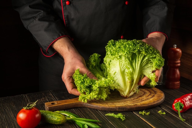 Chef prepares diet food from Lettuce Tearing off green leaves on the kitchen table