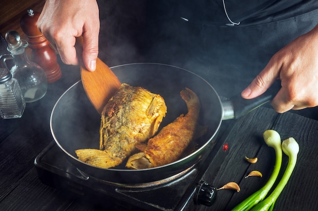 The chef prepares fish in the restaurant kitchen