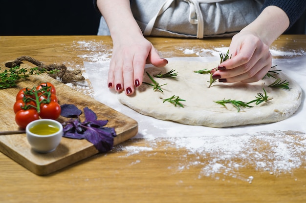 The chef prepares Focaccia, lays rosemary on the dough. 