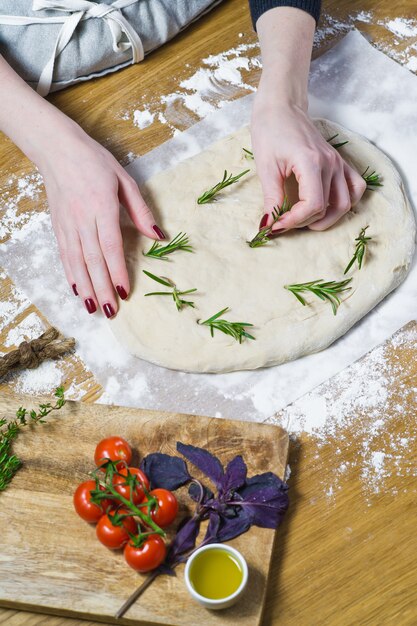 The chef prepares Focaccia, lays rosemary on the dough.  