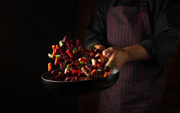 The chef prepares food in a frying pan with steam on a black background