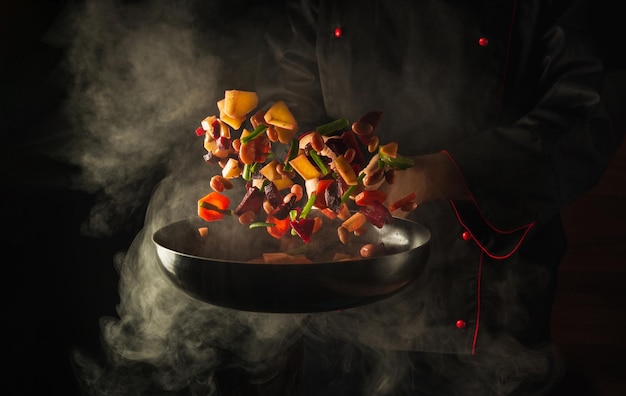 Chef prepares food in a hot pan with steam