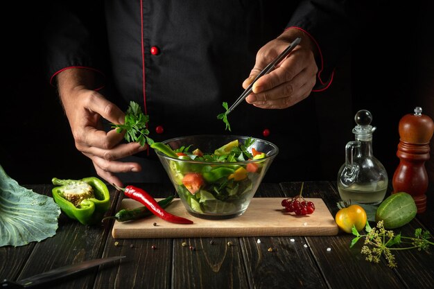 The chef prepares a fresh vegetable salad for a diet breakfast or dinner Menu concept for hotel on black background