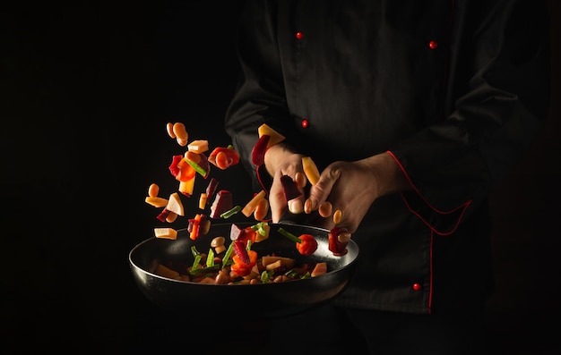 The chef prepares fresh vegetables in a frying pan