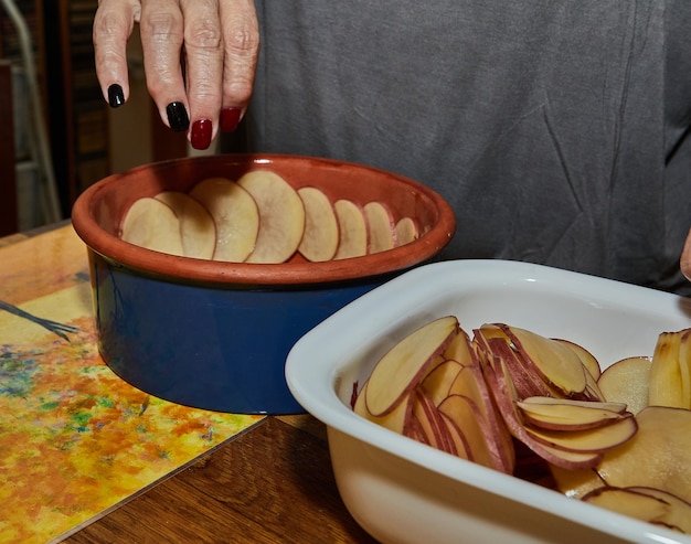 Chef prepares potato gratin in flowershaped ceramic dish