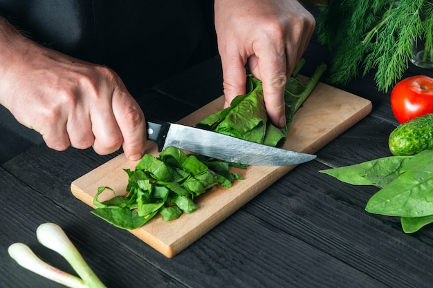 A chef prepares a spinach salad in a restaurant kitchen