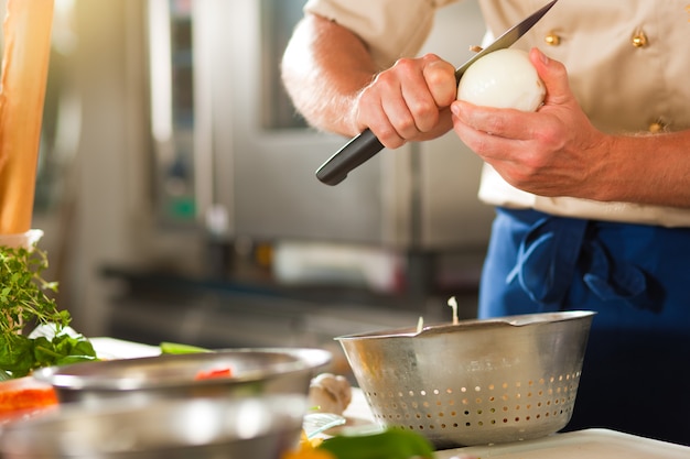 Chef preparing onion in restaurant or hotel kitchen