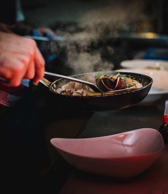 chef presenting ration of clams in gourmet sauce