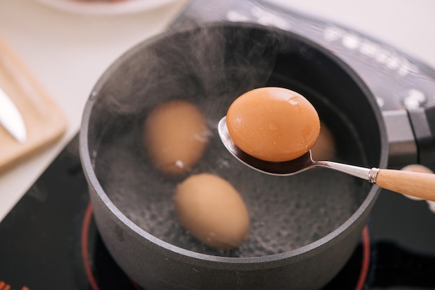 Photo chef putting boiled eggs in cup / cooking sweet brown stewed pork gravy (moo pa-lo) concept