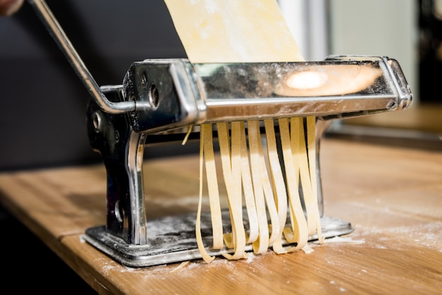 Chef rolling dough with a pasta machine. Pasta maker machine.