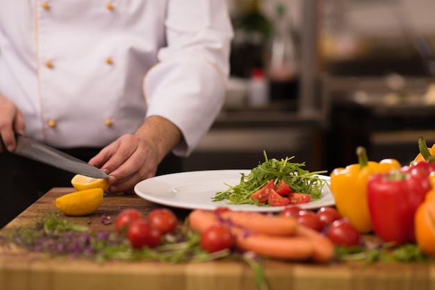 chef serving vegetable salad on plate in restaurant kitchen