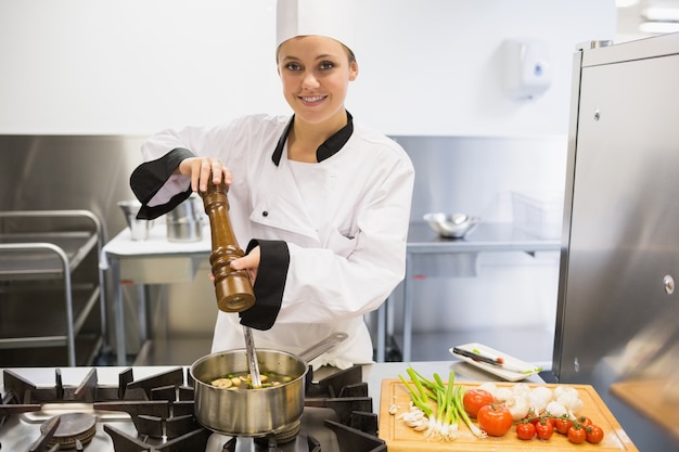 Chef spicing soup and smiling