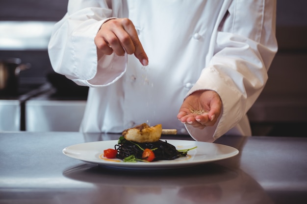 Chef sprinkling spices on dish