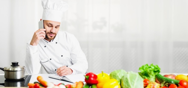 Chef Talking On Phone Receiving Order Standing In Hotel Kitchen