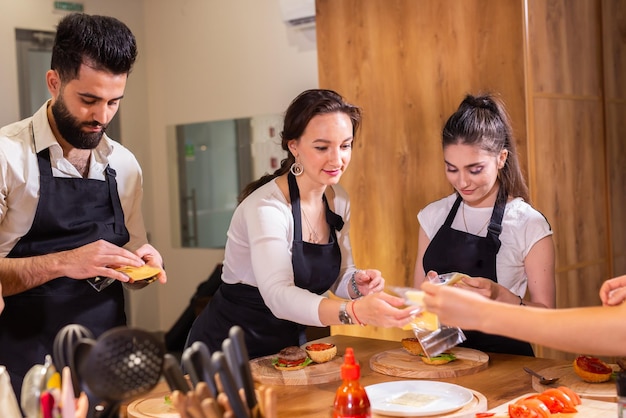 Chef teaching trainees how to make delicious burgers chef cooking meat burgers with beef cheese and